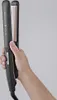 A hand holding a black and rose gold hair straightener against a light gray background. Náhľad obrázku produktu