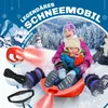Two children on a sled in a snowy environment with winter trees and mountains in the background. Produktbild-Vorschau