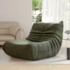 A green floor chair is placed in a living room setting, next to a sofa and a window with sheer curtains. Produktbild-Vorschau