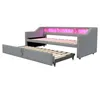 A gray upholstered daybed with a pull-out trundle bed is shown with pink LED lights in the headboard. Voir les images du produit