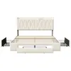 A beige upholstered bed frame with a headboard, showing the slatted mattress support and three pull-out drawers. The drawers are partially extended on both sides and at the foot of the bed. Podgląd zdjęcia produktu