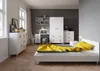 A bedroom with a bed, dresser, desk, and wardrobe. Voir les images du produit