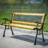 A park bench is shown outdoors on a paved walkway. Podgląd zdjęcia produktu