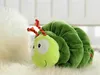 A plush caterpillar toy is lying on a fluffy white surface, possibly a rug or blanket. Produktbild-Vorschau