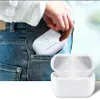 A person is putting a white charging case for AirPods Pro into their jeans pocket. Another charging case is shown open in the foreground. Produktbild-Vorschau