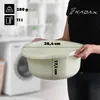 A person is holding a cream-colored plastic basin in a laundry room setting, with a washing machine visible in the background. Dimensions are overlaid on the basin. Voir les images du produit