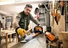 A man is cleaning the blades of a hedge trimmer in a workshop. Produktbild-Vorschau