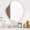 A mirror with a wooden accent is displayed on a shelf with decorative items. Produktbild-Vorschau