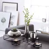 A collection of decorative vases and candle holders arranged on a dark surface in front of a sofa and framed artwork. Produktbild-Vorschau