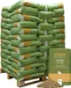 A large stack of green and yellow bags of STROY Strohgranulat on a wooden pallet, with a pile of the product in the foreground. Produktbild-Vorschau