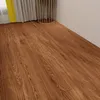 A close-up view of wood-look vinyl flooring in a room, with a curtain and a decorative metal object visible in the background. Anteprima dell’immagine prodotto