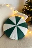 A round green and white pillow sits on a textured white sofa, with fairy lights draped around it and a Christmas tree in the background. Podgląd zdjęcia produktu