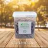 A plastic container filled with straw is placed on a wooden surface with a blurred background of trees. Produktbild-Vorschau