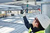 A construction worker is using a cordless drill to attach something to a metal beam. Voir les images du produit