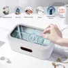 A hand is placing a watch into an ultrasonic cleaner. Several small circular images above show items that can be cleaned. Produktbild-Vorschau