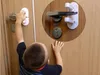 A child is shown trying to open a door that has a child safety lock on the handle. Náhled obrázku produktu