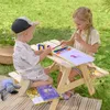 Two children are drawing and playing at a wooden picnic table outdoors on a blanket. Náhled obrázku produktu