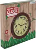 The image shows the front of a product box for a singing birds clock. The box has a wooden plank background and features a clock with illustrations of birds on its face. There is also text and a speaker icon on the box. Náhled obrázku produktu