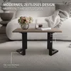 A coffee table with a vase of flowers and books on it, placed on a rug in a living room. Náhľad obrázku produktu
