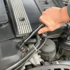 A person's hand is using a torque wrench to work on a car engine. Voir les images du produit