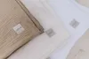 Three folded muslin blankets in different neutral colors, stacked diagonally. Produktbild-Vorschau