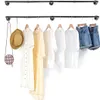 Two industrial-style pipe clothing racks mounted on a white wall, with various clothing items and accessories hanging from them. Produktbild-Vorschau