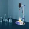 A laboratory setup with a magnetic stirrer and beaker, along with other lab glassware on a dark surface against a blue wall. Náhled obrázku produktu