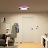A woman sits on a couch reading a book in a hallway with a door, coat rack, and console table. Produktbild-Vorschau