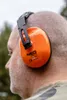 Close-up of a person wearing orange ear protection headphones. Produktbild-Vorschau