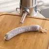 A sausage stuffer is shown with a partially filled sausage casing on a wooden cutting board. Produktbild-Vorschau