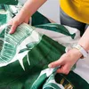 Hands holding a piece of fabric with a banana leaf pattern. Podgląd zdjęcia produktu