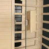 Close-up view of the interior of a wooden sauna cabin, showing heating elements behind grates, a glass door, and a wooden handle. Produktbild-Vorschau