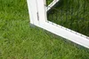 Close-up of the base of a white wooden pet hutch with a metal trim, resting on green grass. Voir les images du produit