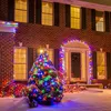 A brick house decorated with Christmas lights and a snow-covered tree in front. Produktbild-Vorschau