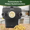 A Philips pasta maker attachment is shown on a wooden surface, with freshly made pasta in the foreground. The background is a blurred kitchen setting. Produktbild-Vorschau