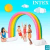 Children playing with a rainbow sprinkler in a backyard. Produktbild-Vorschau