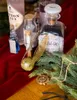 A collection of Harry Potter-themed items, including potion bottles, a Golden Snitch replica, and a necklace, arranged on a red cloth and wooden surface with evergreen branches. Náhled obrázku produktu