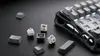 A close-up shot of a disassembled mechanical keyboard with keycaps and switches scattered around the keyboard base. Produktbild-Vorschau