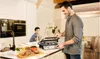 A father and son are in a kitchen, with the father using a grill. Podgląd zdjęcia produktu