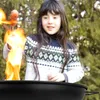 A young girl is grilling sausages over a fire in a garden. Produktbild-Vorschau