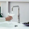 A hand holding a glass under a modern kitchen faucet, filling it with water. Anteprima dell’immagine prodotto