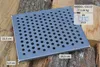 A metal grate with holes is placed on a pile of chopped wood. Voir les images du produit