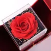 Konservierte rote Rose in einer durchsichtigen Acrylbox, eingebettet in eine rote Geschenkbox mit goldenen Akzenten Anteprima dell’immagine prodotto