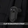 A close-up of a small black camera clipped to a black backpack strap. Náhled obrázku produktu