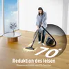 A woman is vacuuming a wooden floor in a bright room with large windows. Produktbild-Vorschau