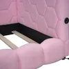 A close-up view of a pink upholstered bed frame, showing the hexagonal pattern on the headboard and the rounded shape of the footboard. Wooden slats for the mattress are visible. Náhled obrázku produktu
