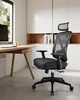 A black office chair is positioned next to a wooden desk in a modern office setting with shelves in the background. Náhled obrázku produktu
