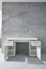 A white desk with drawers and cabinets against a concrete wall. Produktbild-Vorschau