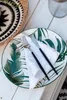 A table setting with a tropical-themed plate, cutlery, and napkin. Náhľad obrázku produktu