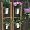 Four metal buckets with plants hanging on a wooden frame, with a purple hanging planter in the background. Produktbild-Vorschau